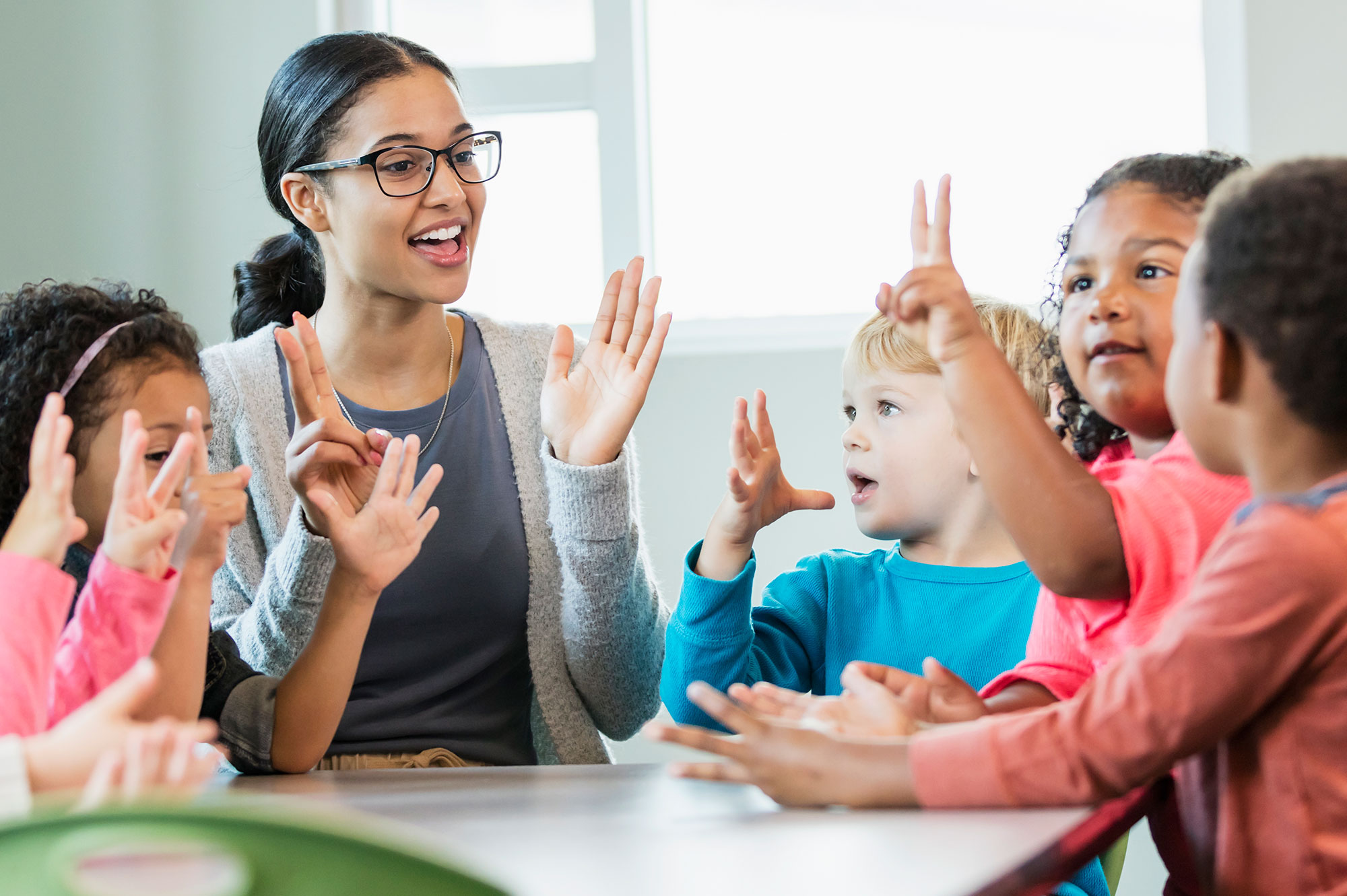 Group of kindergarten kids clapping with a teacher.